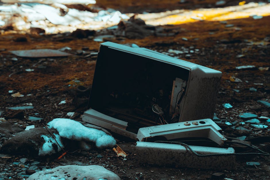 Broken TV screen in an abandoned, desolate urban environment amidst debris and wreckage.
