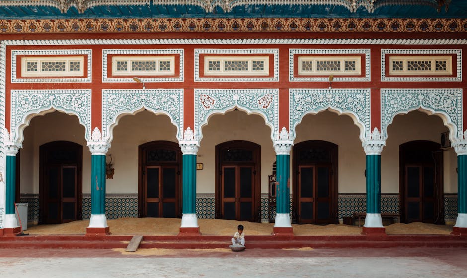 A child in traditional attire rests outside a colorful mosque in Faisalabad, Pakistan.
